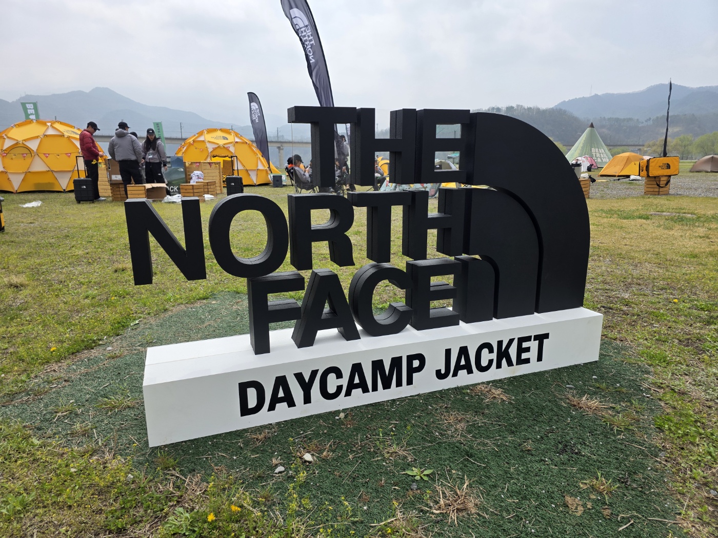 THE NORTH FACE 블랙 로고와 DAYCAMP JACKET 문구가 보이는 야외 행사 완성사진