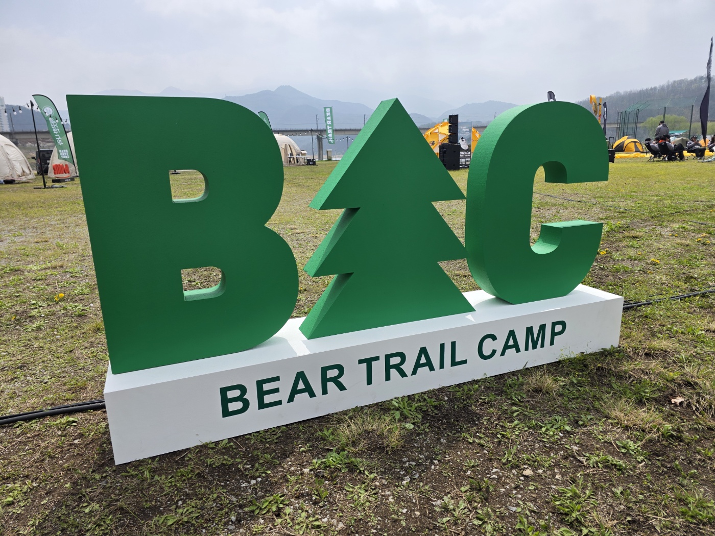 야외 행사장에 설치된 그린 BTC 조형물과 BEAR TRAIL CAMP 기단
